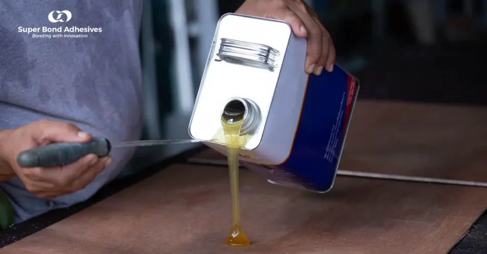 Worker pouring thick rubber-based adhesive from a metal container onto a surface for industrial bonding.