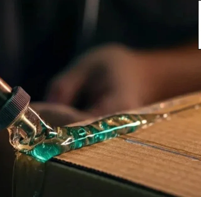 HMPSA Adhesive being applied by a glue gun